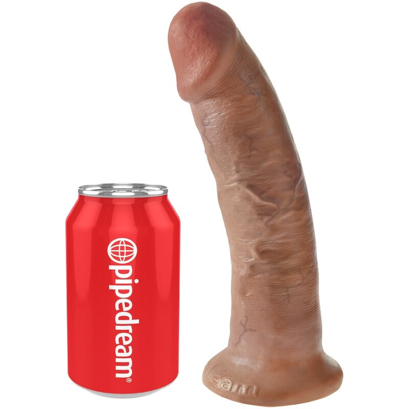 Gode realiste King Cock caramel incline pres d'une canette Pipedream rouge pour l'echelle de taille, gland net et veines, base ventouse, format compact, modele fait main effet peau.