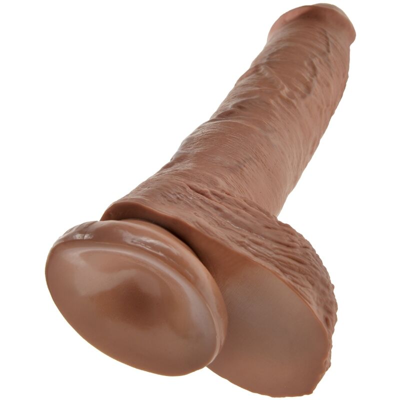 Gros plan en plongee de la base d'un gode realiste King Cock, testicules moules tres detailles et amorce du fut veine, teinte chair caramel, modele fait main effet peau, base ventouse.