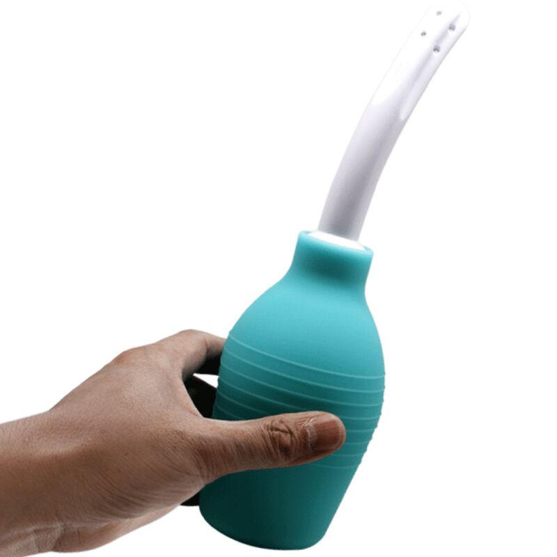 Poire de lavement anale Mr Play turquoise tenue en main, pression de l'ampoule et buse recourbee blanche, accessoire d'hygiene intime pour preparer la zone anale.