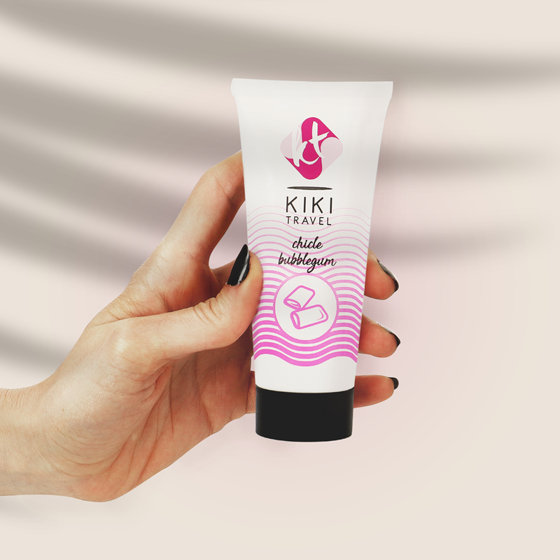 Tube de lubrifiant gourmand fraise Kiki Travel tenu en main pour montrer son format compact, base eau hydratante vegan, saveur chewing-gum, compatible preservatifs latex.