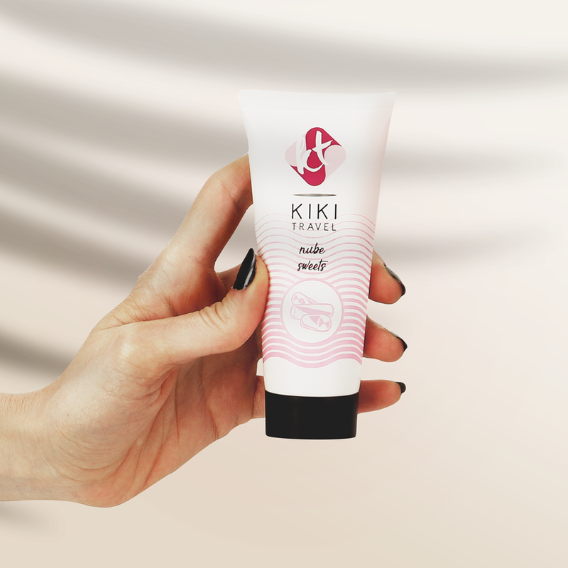 Tube de lubrifiant gourmand bonbon Kiki Travel tenu en main pour montrer son format compact, base eau hydratante vegan, saveur sucree, compatible preservatifs latex.