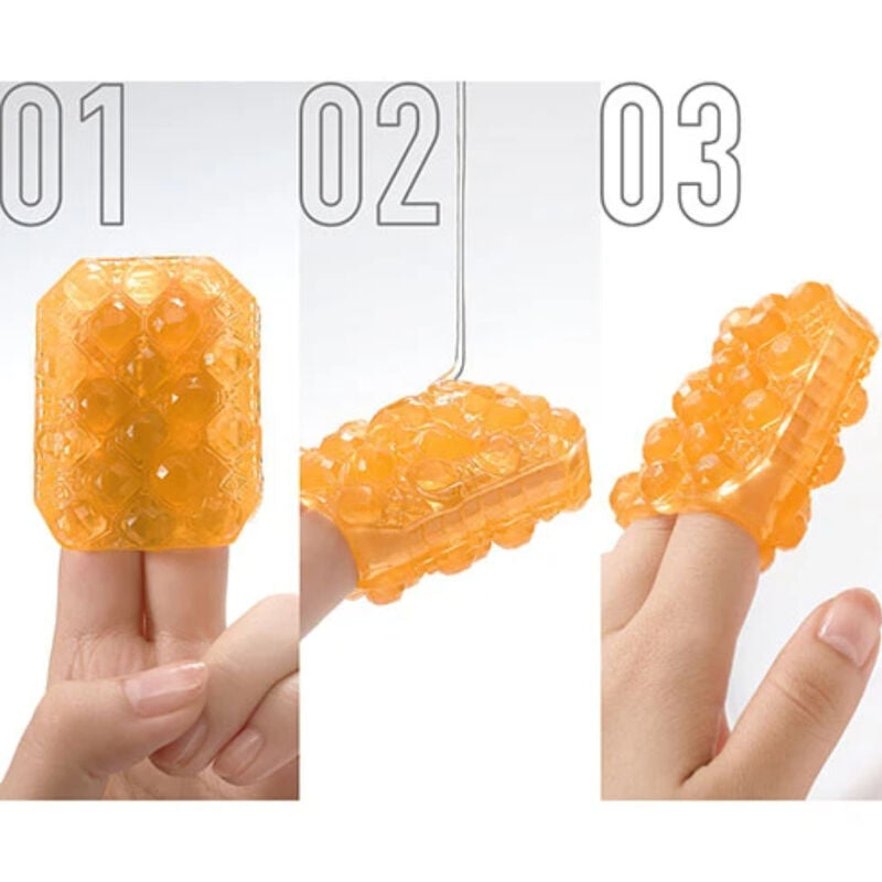 Trois vues du dé Tenga Uni Topaze orange porté au doigt, démonstration de sa texture en relief arrondie et de la souplesse du masturbateur unisexe en élastomère.