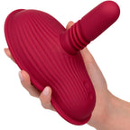 Rider Massager rouge foncé tenu en main sous un autre angle, tige centrale émergeant des doigts refermés sur la base.