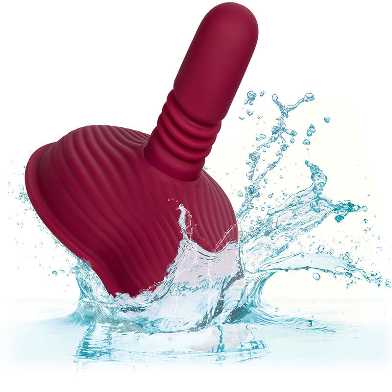 Rider Massager rouge foncé en suspension dans une éclaboussure d'eau, illustrant l'étanchéité du produit.