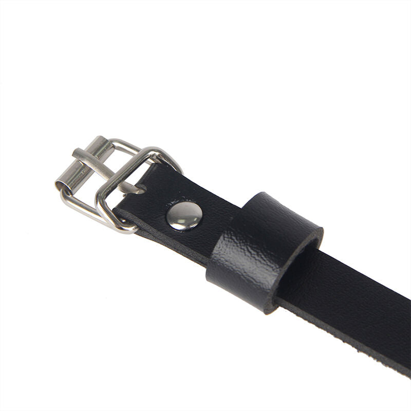 Gros plan de la boucle metal a ardillon et de la laniere en cuir noir du harnais Subblime, finition robuste du cuir graine et detail du fermoir, presentation produit sans modele.