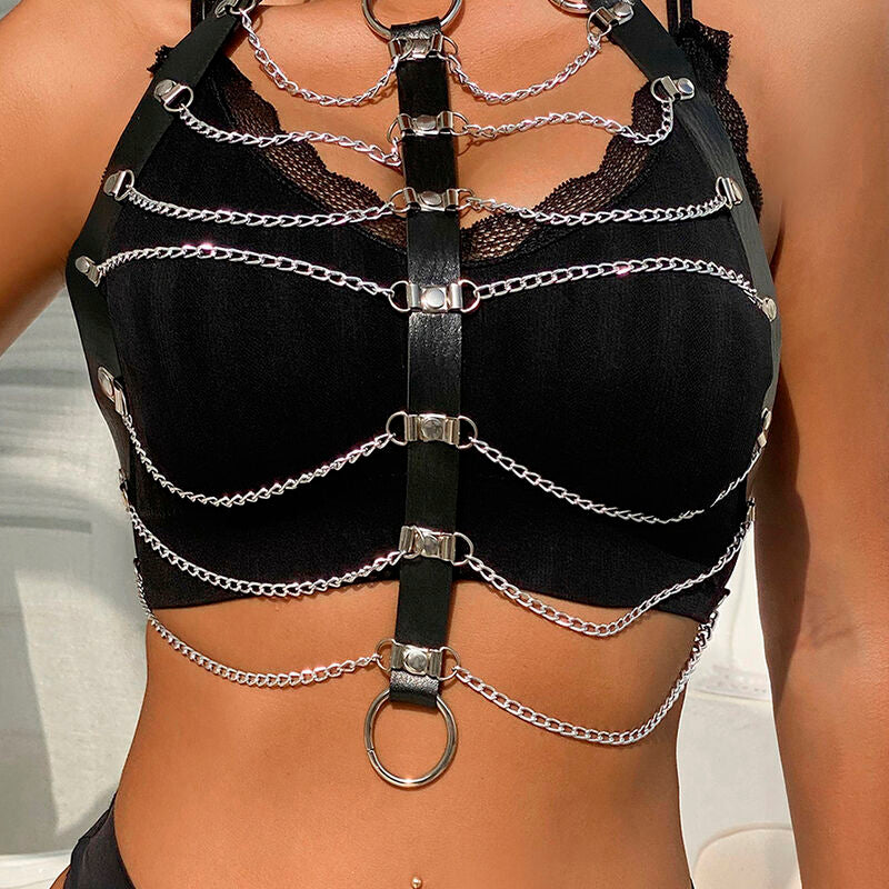 Soutien-gorge harnais en cuir et chaines argentees porte sur le buste, anneau central et drapes encadrant la poitrine, allure fetichiste glamour Subblime.