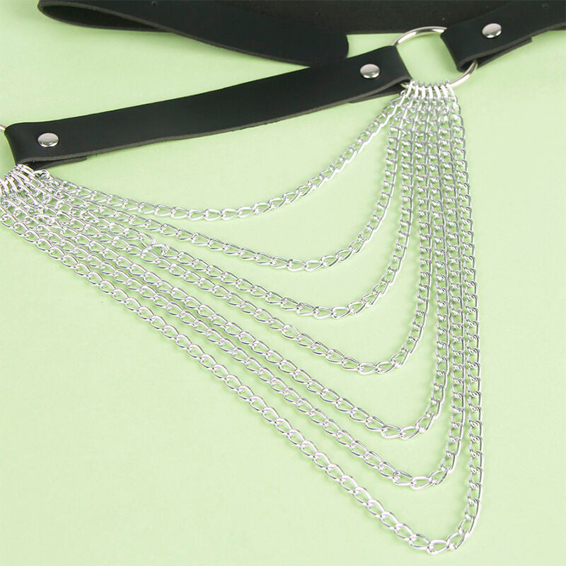 Detail des drapes de chaines argentees suspendus a la sangle en cuir noir de la ceinture Subblime, jeu graphique fetichiste presente sur fond vert.