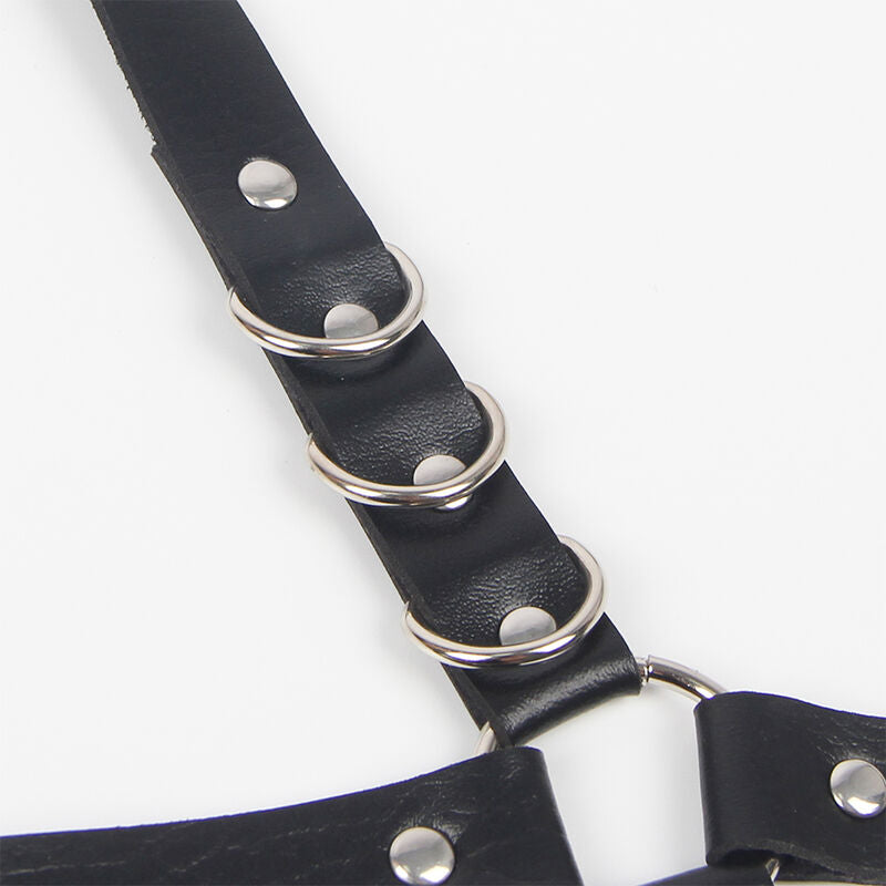 Detail des anneaux metal rythmant la sangle en cuir noir du harnais jarretieres Subblime, boutons pression et finition fetichiste sur fond clair.