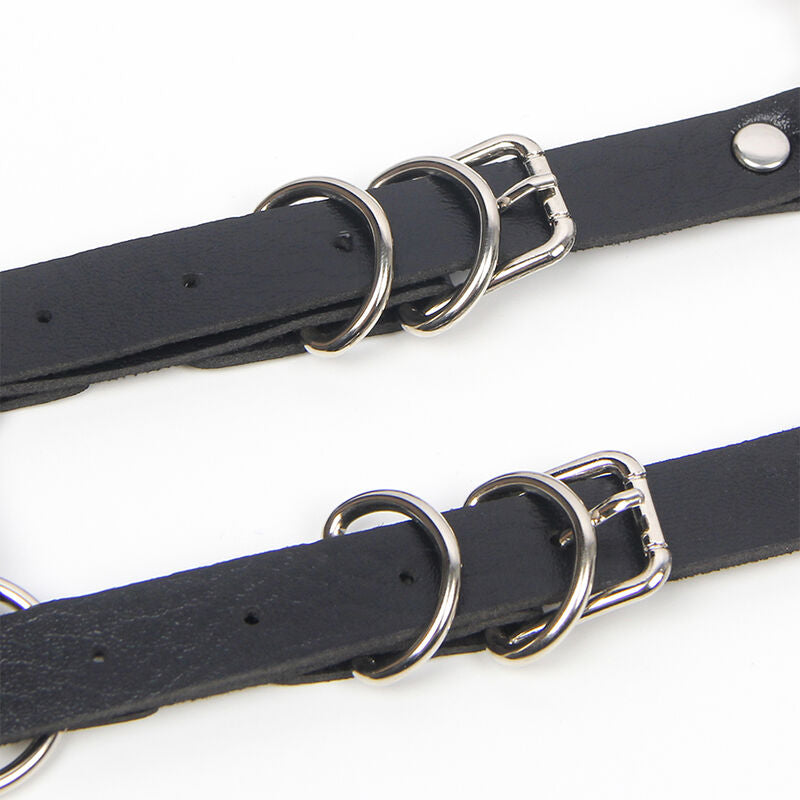 Vue rapprochee des sangles en cuir noir a doubles boucles metalliques argentees du harnais de corps Subblime, reglage ajustable et finition fetichiste tres soignee.