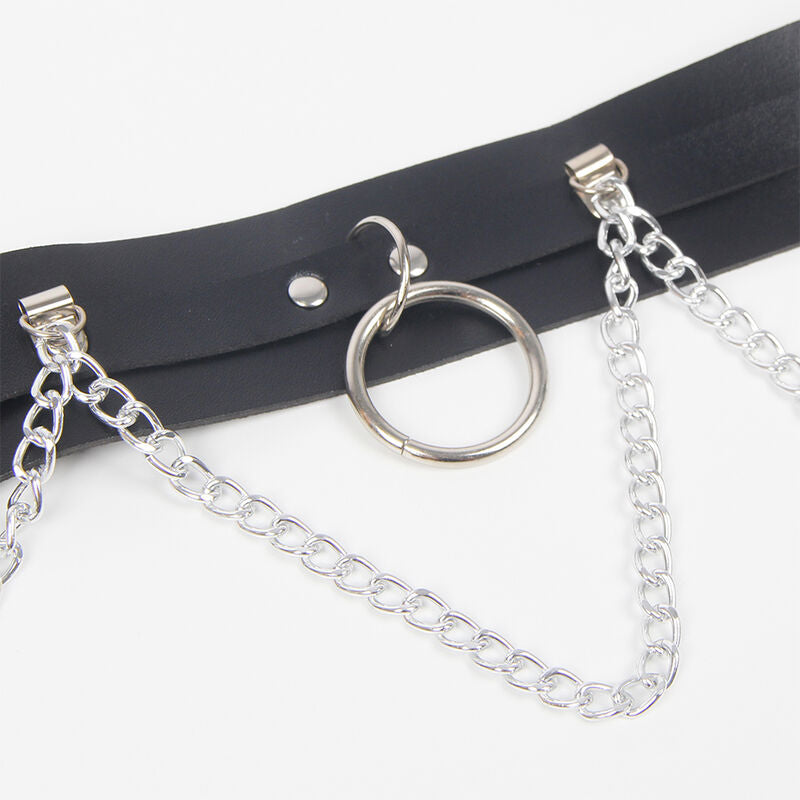 Detail du harnais cuir Subblime avec son grand anneau metal argente et sa chaine suspendue, bouton-pression sur la sangle noire epaisse, finition fetichiste soignee.