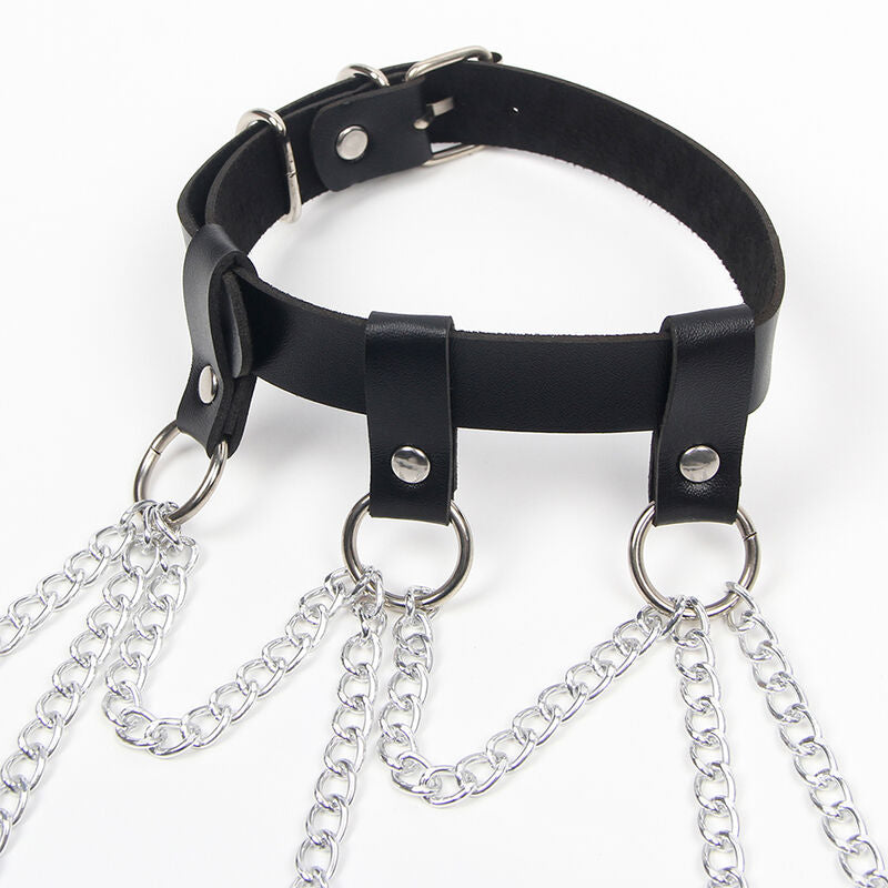 Gros plan sur le collier en cuir noir a bouton-pression du harnais etoile Subblime, chaines metal argentees suspendues et anneaux decoratifs, finition fetichiste graphique.