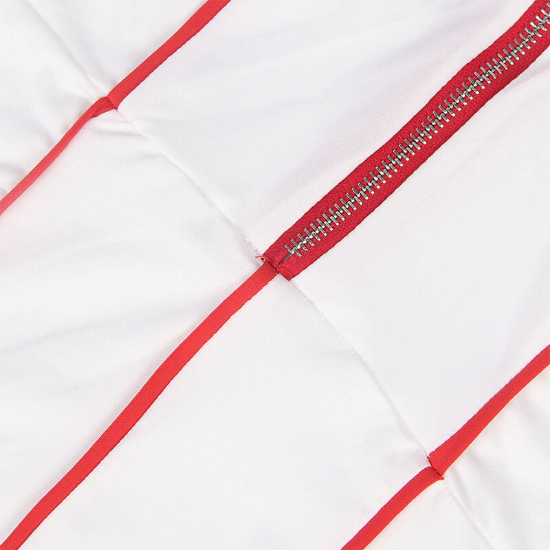 Détail de la fermeture éclair et des liserés rouges croisés du costume d'infirmière Subblime sur tissu blanc, glissière métal en gros plan à plat.