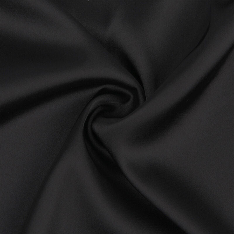 Macro du satin noir du babydoll Subblime, surface lisse et brillante aux plis souples mettant en avant la qualite et le tombe du tissu satine, gros plan detaille sans modele.