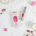 Baume clitoridien Clit Pwr fraise mis en scene avec boite et eclats decoratifs roses, flacon airless Secret Play, formule chauffante et picotante a usage externe.