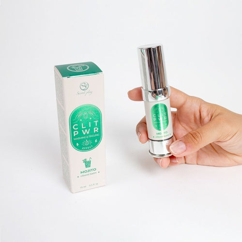 Flacon airless du baume clitoris Clit Pwr Mojito tenu en main pres de sa boite verte. Soin stimulant a la sensation de chaleur et picotement, conditionnement airless 15 ml.