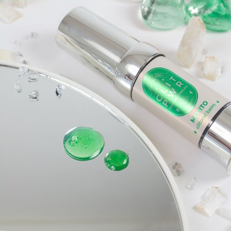 Goutte de baume Clit Pwr Mojito vert deposee sur un miroir pres du flacon airless argente. Texture gel stimulant clitoris a effet chauffant et picotant, saveur mojito.
