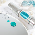 Goutte de baume Clit Pwr noix de coco bleue deposee sur un miroir pres du flacon airless. Gel stimulant clitoris a effet chauffant et picotant, absorption rapide, usage externe.