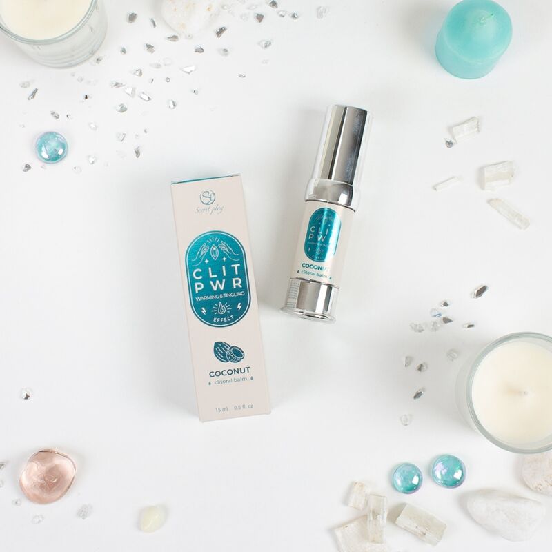 Baume stimulant clitoris Clit Pwr noix de coco presente avec sa boite bleue parmi cristaux et bougie. Soin chauffant picotant 15 ml en flacon airless pour le plaisir feminin.