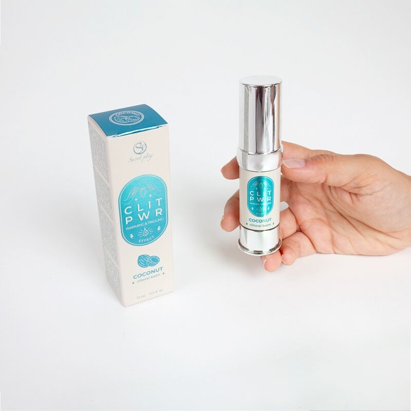 Flacon airless du baume clitoris Clit Pwr noix de coco tenu en main pres de sa boite bleue. Soin stimulant externe a sensation de chaleur et picotement, texture non collante.