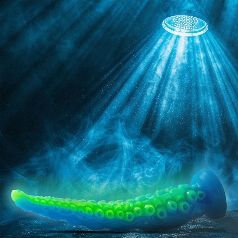 Gode tentacule fluorescent bleu et vert pose sous un faisceau de lumiere bleutee, mise en scene marine evoquant la lueur dans le noir et la texture de ventouses souple