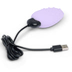 Mimi Deux lilas relié à son câble de charge USB noir enroulé en boucle, galet texturé posé à droite, illustration de la recharge USB du masseur clitoridien sur fond blanc épuré.