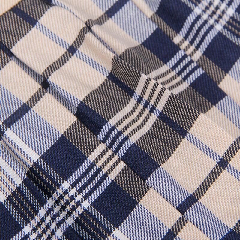 Macro du motif a carreaux croises bleu marine et beige du tissu de la jupe du costume d'ecoliere Subblime, texture maille extensible.