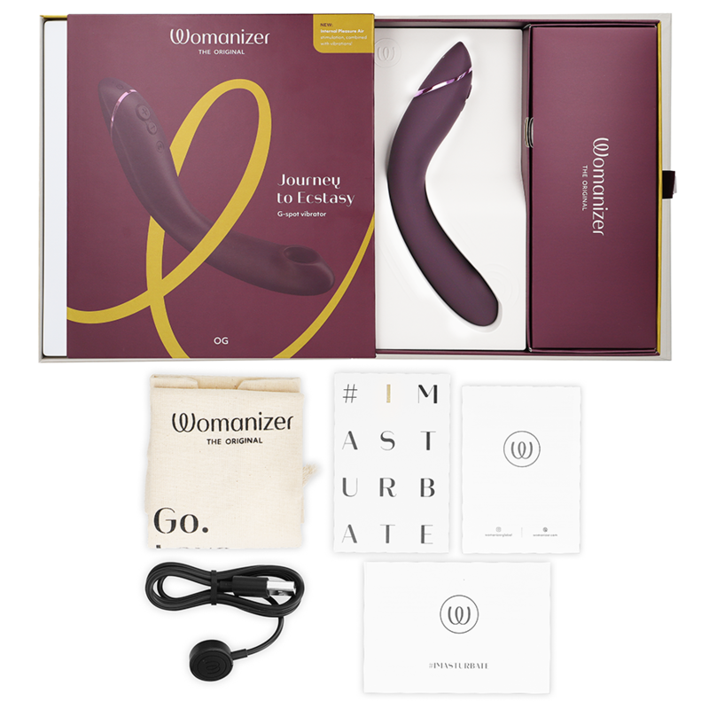 Coffret bordeaux ouvert du Womanizer OG, câble de charge USB, sachet et cartes de notice présentés à plat, stimulateur G-spot rechargeable par ondes d'air.