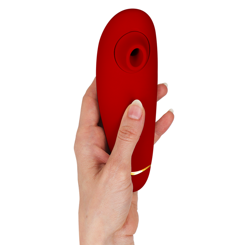 Stimulateur clitoridien Womanizer Premium 2 rouge tenu verticalement dans une main, liseré doré et embout d'aspiration en silicone vers le haut. Format ergonomique compact.