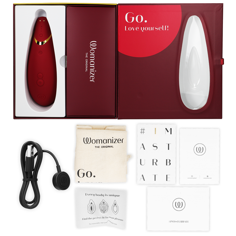 Coffret rouge ouvert du Womanizer Premium 2, câble de charge, sachet et cartes de notice à plat, stimulateur clitoridien rouge rechargeable par ondes d'air.