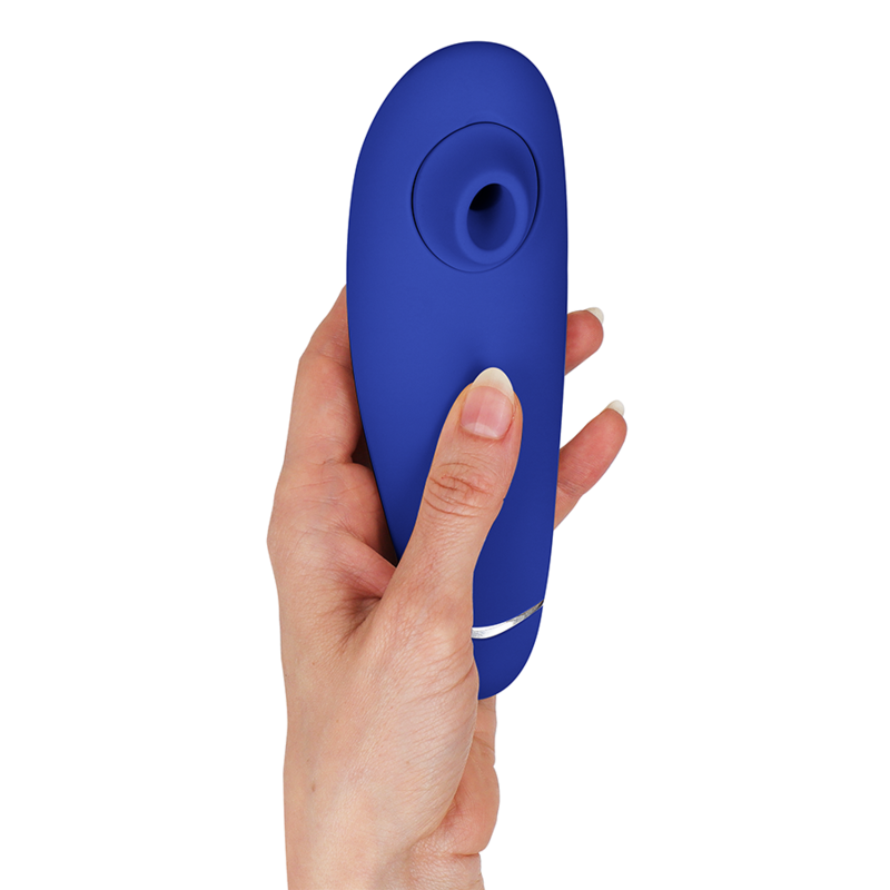 Stimulateur clitoridien Womanizer Premium 2 bleu tenu verticalement dans une main, liseré argenté et embout d'aspiration en silicone vers le haut. Format ergonomique compact.
