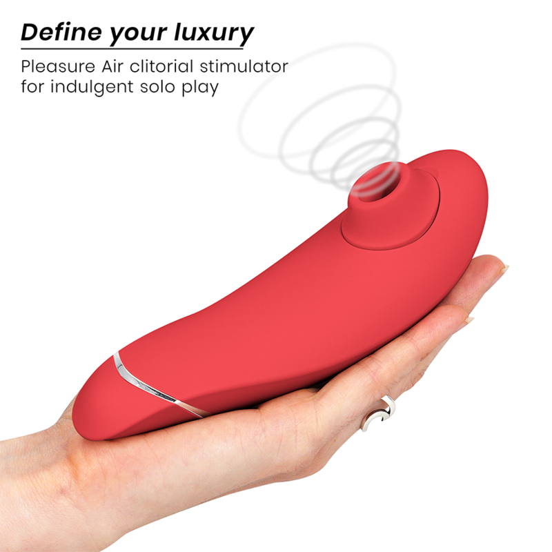 Main ouverte présentant le Womanizer Premium 2 rose au liseré argenté posé à plat, embout d'air pulsé vers la gauche, schéma d'ondes d'air clitoridien.