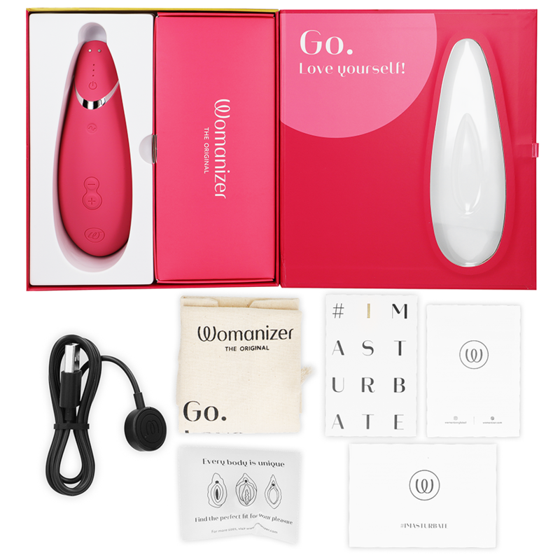 Coffret rose ouvert du Womanizer Premium 2, câble de charge, sachet et cartes de notice à plat, stimulateur clitoridien rose rechargeable par ondes d'air.