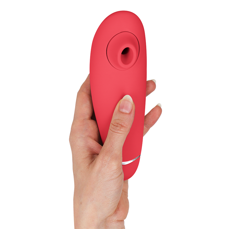 Stimulateur clitoridien Womanizer Premium 2 rose tenu verticalement dans une main, liseré argenté et embout d'aspiration en silicone vers le haut. Format ergonomique compact.