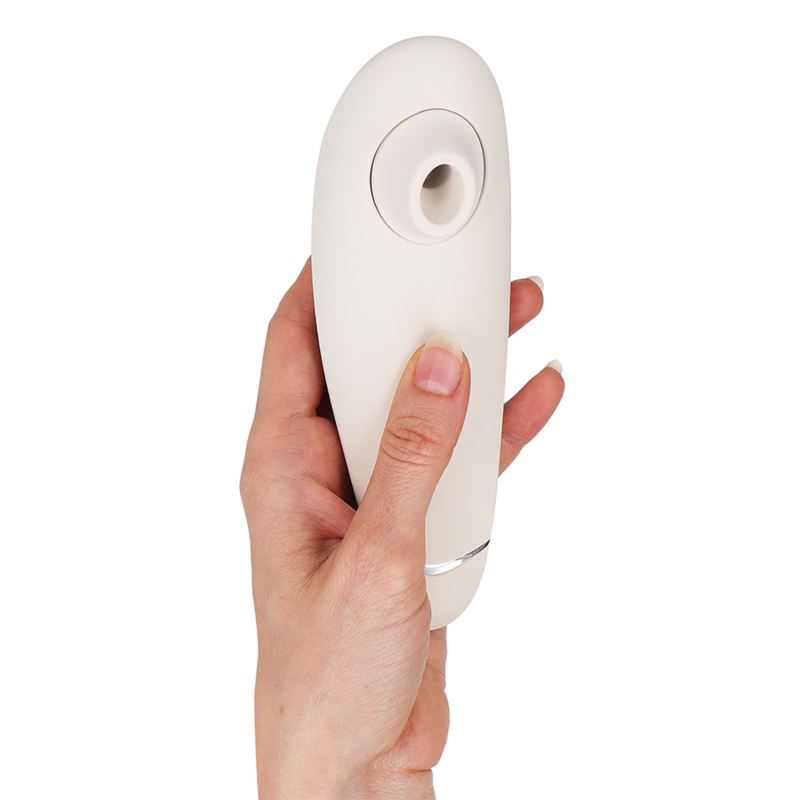 Stimulateur clitoridien Womanizer Premium 2 blanc tenu verticalement dans une main, liseré argenté et embout d'aspiration en silicone vers le haut. Format ergonomique compact.