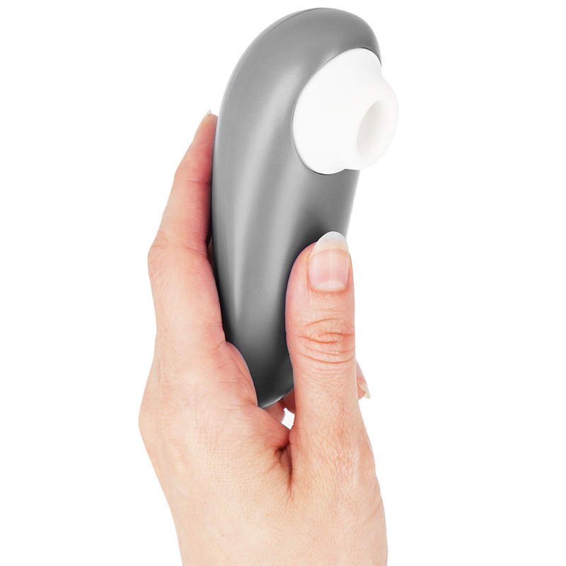 Stimulateur clitoridien Womanizer Starlet 3 gris tenu à la verticale dans une main, embout d'aspiration blanc en silicone orienté vers le haut. Format ergonomique compact.