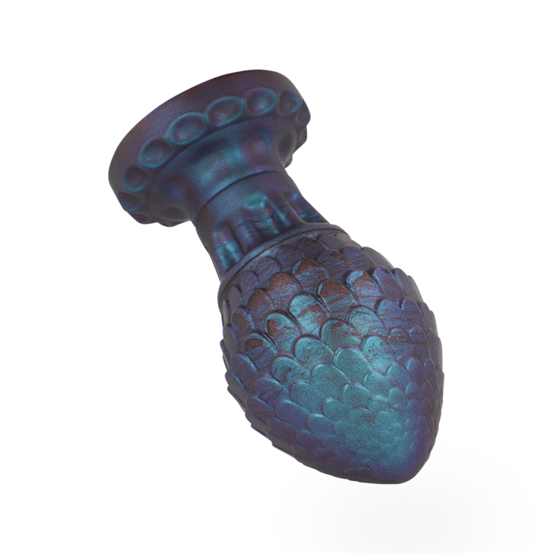 Plug anal œuf de dragon en silicone ecailleux bleu vert vu de trois quarts, forme bulbeuse sur col evase, texture facon coquille pour une stimulation douce.
