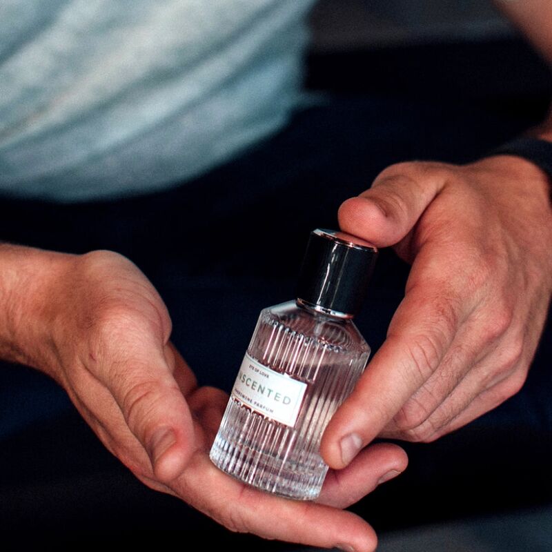 Flacon de parfum aux phéromones non parfumé Unscented presente entre deux mains, vaporisateur transparent 50 ml Eye Of Love, formule inodore concue pour seduire tous les genres.