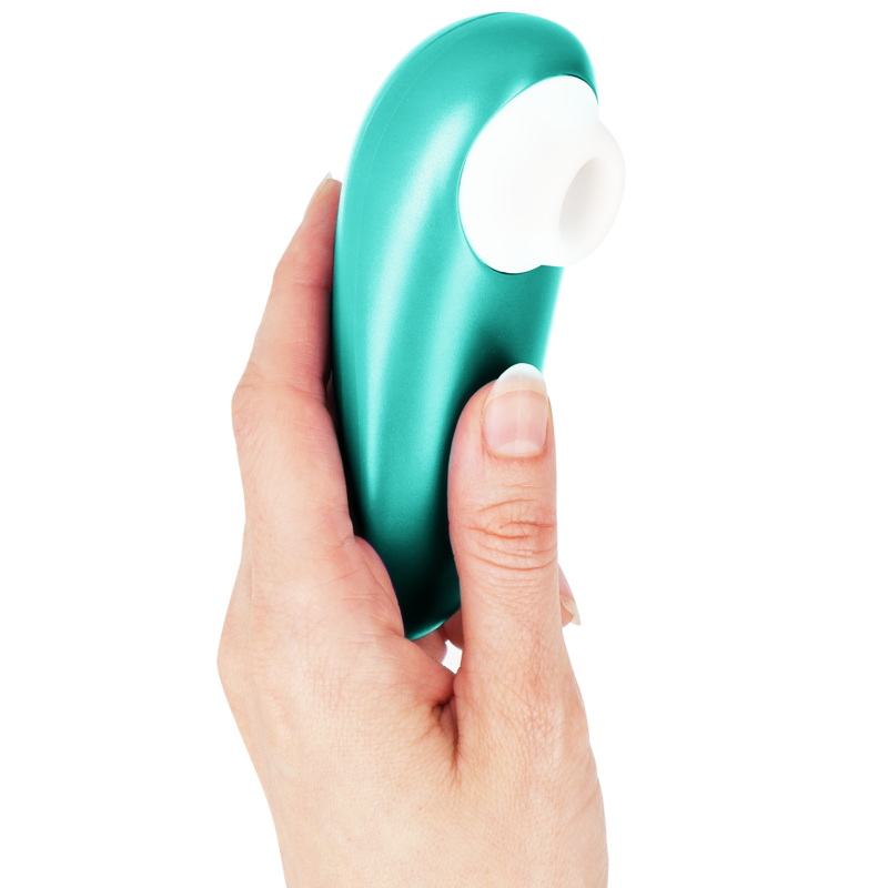 Stimulateur clitoridien Womanizer Starlet 3 turquoise tenu à la verticale dans une main, embout d'aspiration blanc en silicone vers le haut. Format ergonomique compact.