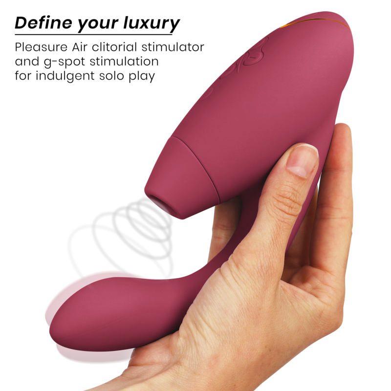 Main tenant le Womanizer Duo 2 bordeaux, tête à ondes d'air et tige courbée vibrante en silicone, schéma d'ondes d'air pour double stimulation. Format ergonomique compact.