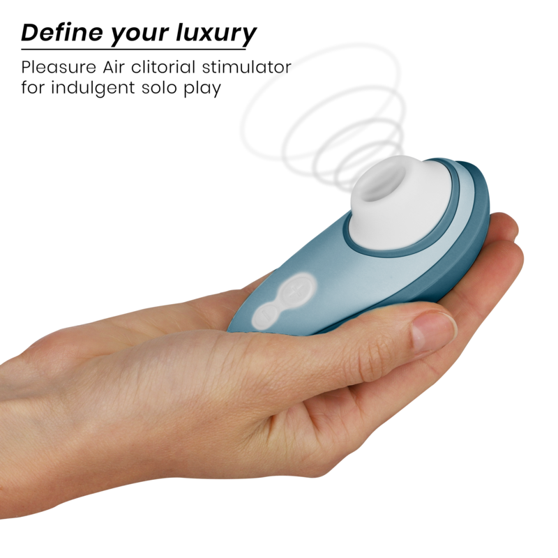 Main tenant le Womanizer Liberty 2 bleu acier, embout d'aspiration blanc orienté vers le haut, stimulateur clitoridien portatif par ondes de pression d'air.