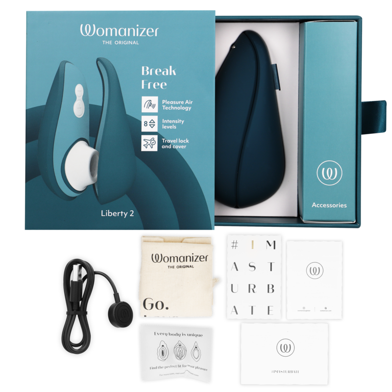 Coffret bleu du Womanizer Liberty 2 ouvert avec stimulateur dans son écrin, câble USB, pochette et cartes d'accessoires disposés autour de la boîte Break Free.