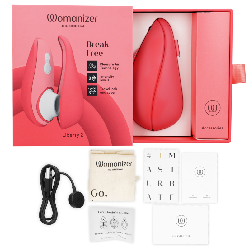 Coffret corail du Womanizer Liberty 2 ouvert avec stimulateur rose dans son écrin, câble USB, pochette et cartes d'accessoires, mention Break Free sur la boîte.