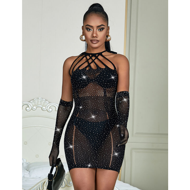 Robe resille noire a strass Subblime portee devant un lit : maille transparente brillante moulante, gants longs pailletes, silhouette revelee par la transparence.