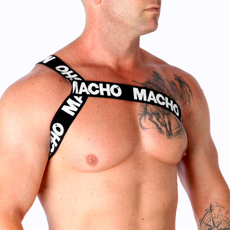 Harnais homme Macho à sangles jaunes vu de trois quarts sur torse nu musclé tatoué, bande logo sur l'épaule, illustrant la coupe ajustée et le look fétichiste affirmé près du corps.