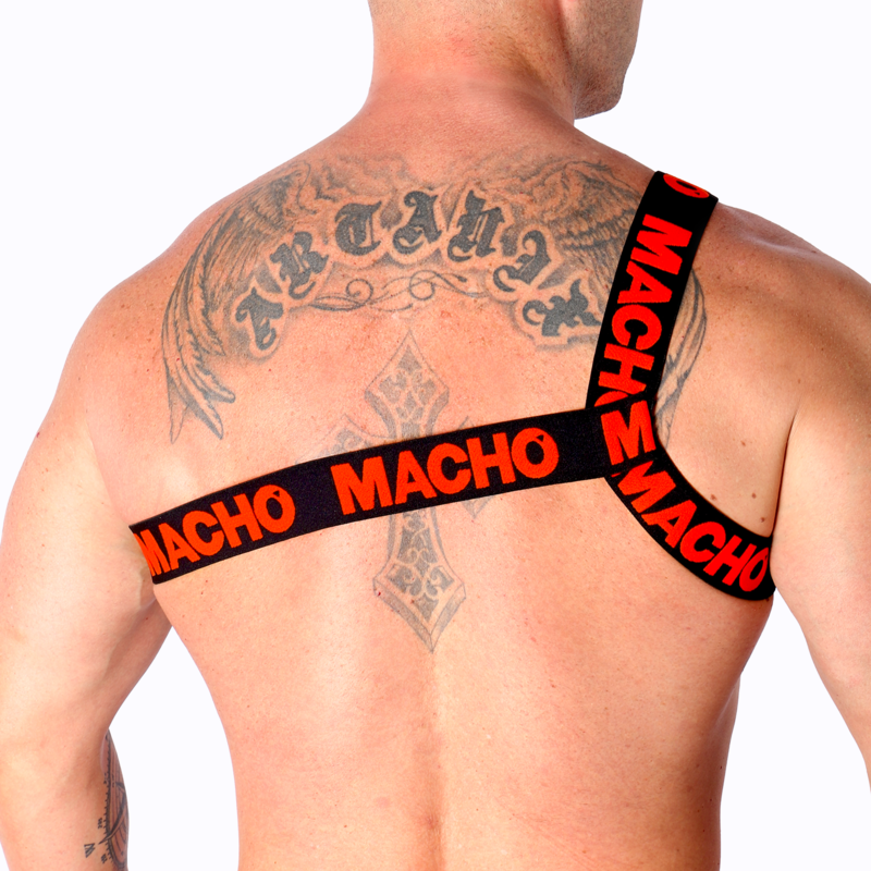Harnais homme Macho à sangles jaunes vu de dos sur dos très tatoué musclé, bandes logo croisées entre les omoplates, affirmant un style fétichiste structurant près du corps.