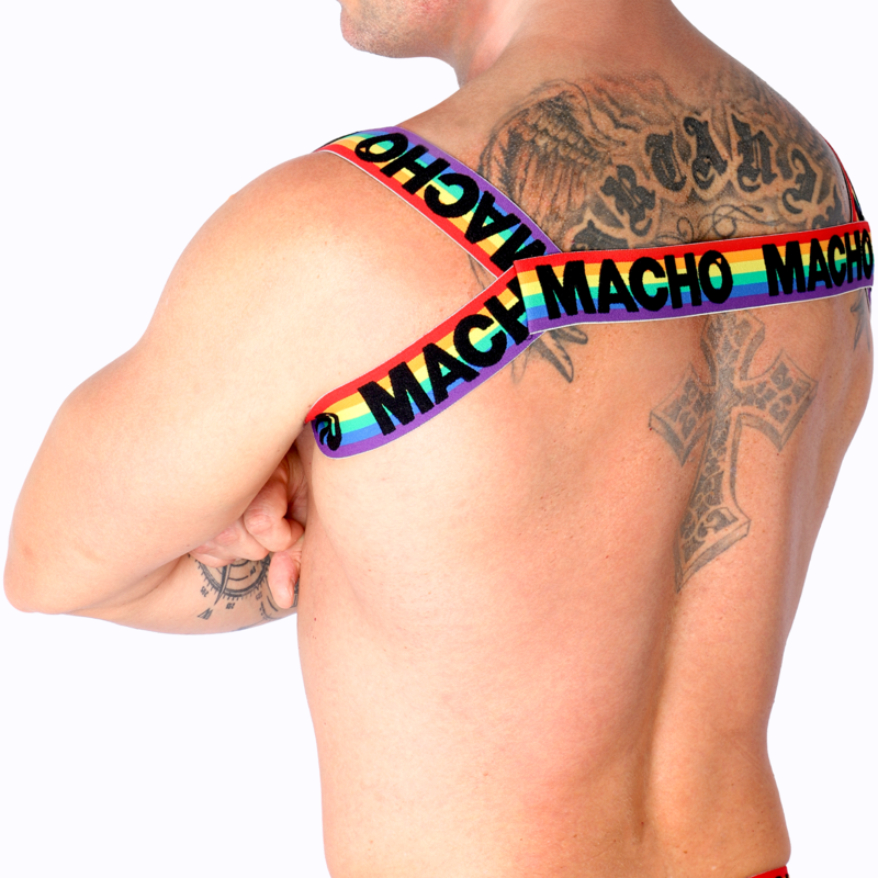 Harnais homme Macho arc-en-ciel porté en gros plan sur épaule et torse nus musclés tatoués, sangles colorées, illustrant le maintien et le style fétichiste coloré du modèle.