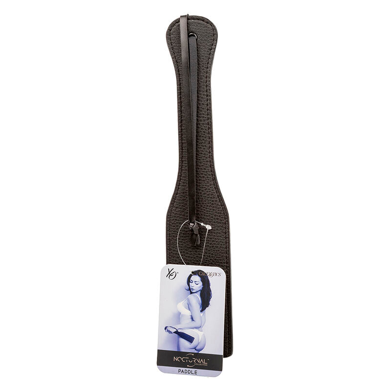 Paddle en cuir noir Nocturnal avec son etiquette XO accrochee, vue produit de la raquette de fessee CalExotics a double couture et dragonne.