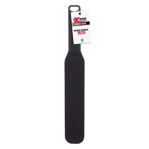 Paddle de fessee en silicone noir suspendu a son etiquette Extreme Rush Gear Spiked Paddle, manche long et surface a picots pour moduler caresse et stimulation.