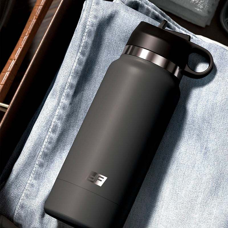 Masturbateur gourde isotherme noire posee sur un jean, mise en scene lifestyle evoquant une simple bouteille sportive pour un rangement parfaitement discret.