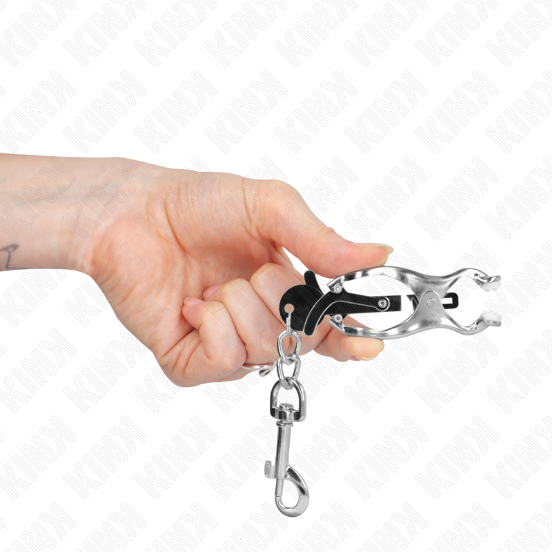 Pince a tetons clover en metal tenue en main avec son mousqueton pivotant, gros plan sur le mecanisme a pression progressive de cet accessoire BDSM.